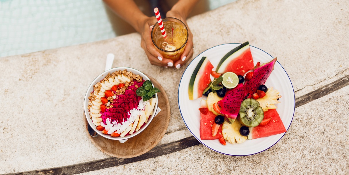 mujer-elegante-traje-tropical-disfrutando-comida-vegetariana-tazon-batido-plato-fruta-limonada-vista-superior.jpg